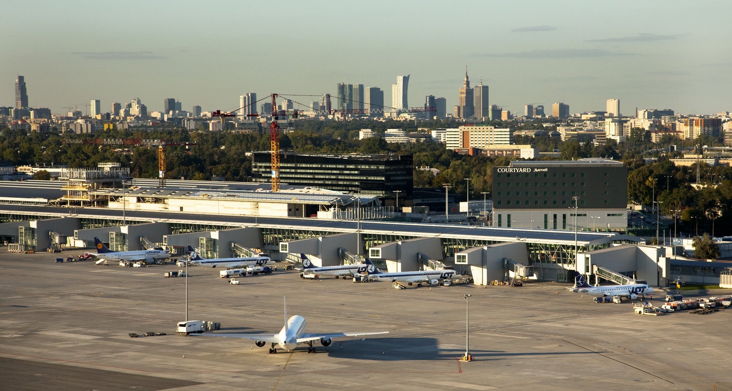 płata lotniska zaparkowane samoloty port lotniczy im. F. Chopina z widokiem na panoramę Warszawy