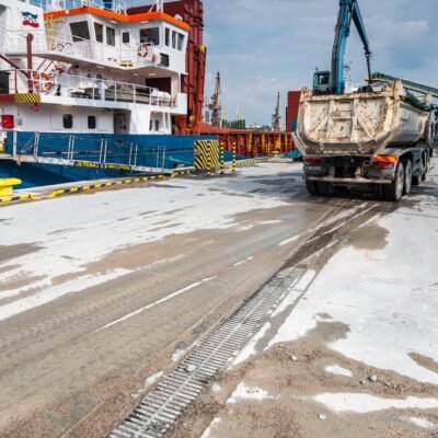 ciąg betonowego prefabrykowane koryta odwadniającego na nabrzeżu przemysłowym w Gdańsku, wywrotka oraz statek w tle